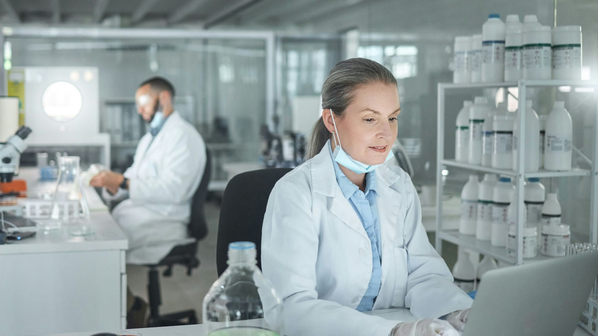 Mujer con bata de laboratorio trabajando en un ordenador en un laboratorio