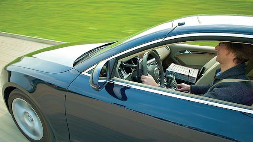 Un uomo alla guida dell'auto con un dispositivo di test Simcenter.