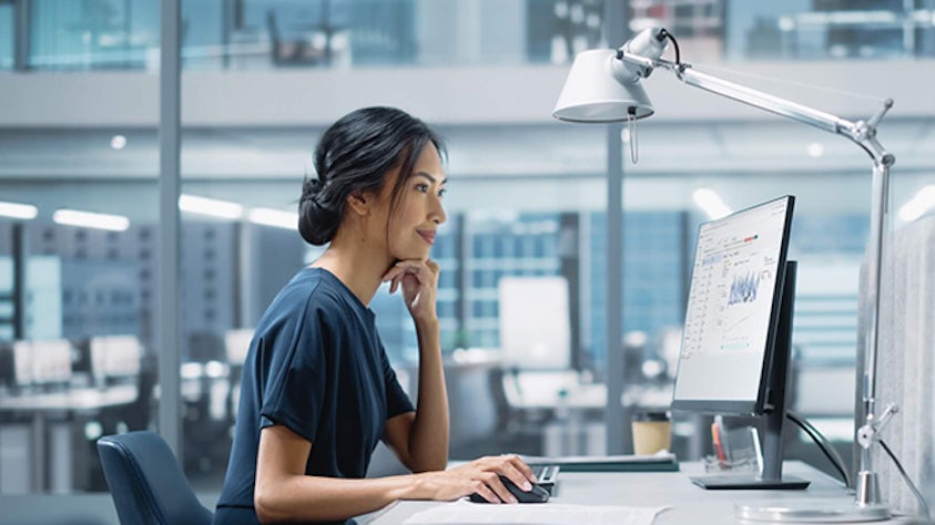 A manufacturing operations IT employee sitting at a desk looking at a computer.