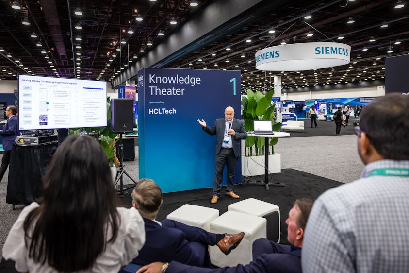 A Siemens partner stands in front of group in a Realize LIVE Knowledge Theater.