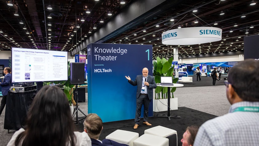 A Siemens partner stands in front of group in a Realize LIVE Knowledge Theater.