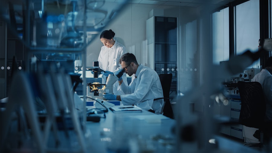 Two scientists in a laboratory looking at a microscope.