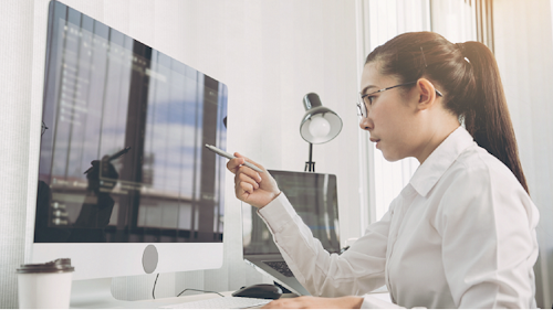 製品データ管理のベストプラクティス: パソコンの画面を見ながら作業をする女性