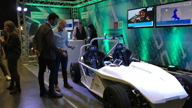 Two people examine a concept car on display at a convention