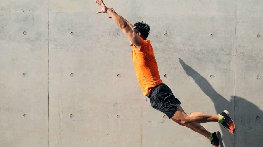 Homme en T-shirt orange qui saute vers la gauche