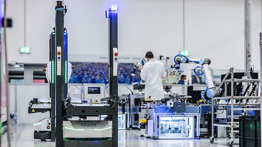Una fábrica en funcionamiento en la cual unos brazos robóticos trabajan en la gestión de inventario.