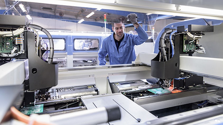 Un empleado de fábrica trabajando en un sistema de ejecución de fabricación electrónica.