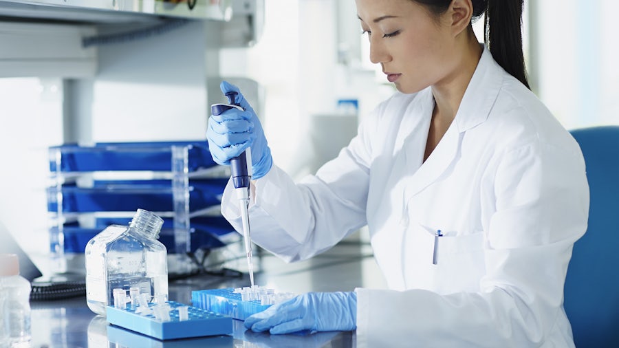 Laboratory technician filling multiple vials with a liquid in a lab setting. 