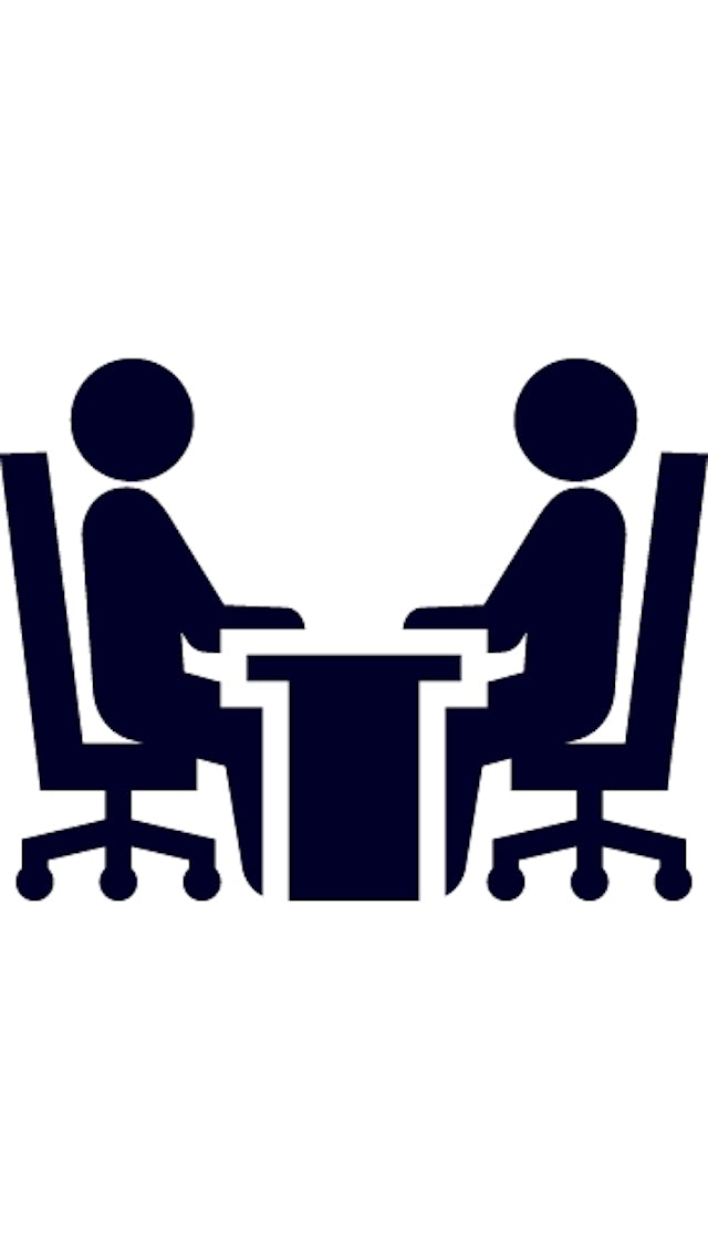 Icon of two people on either side a desk facing each other such as in a meeting.