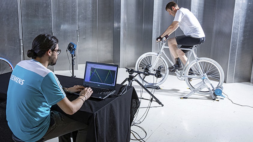 Uomo che utilizza la correlazione digitale di immagini (DIC) per misurare i dati 3D a tutto campo di una bicicletta.