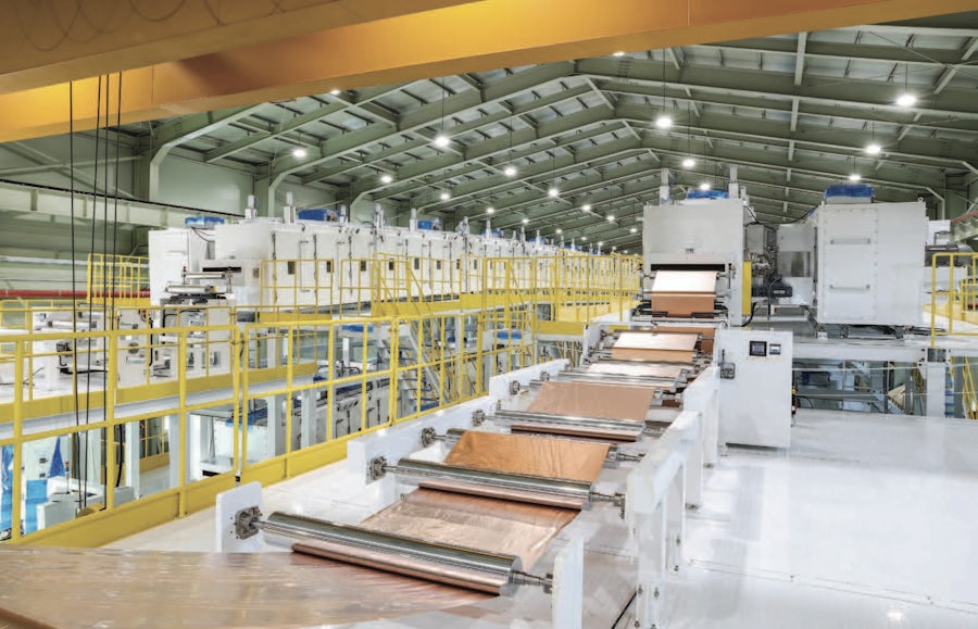A battery electrode conversion machine with a spool of copper sheeting spread down they conveyor.