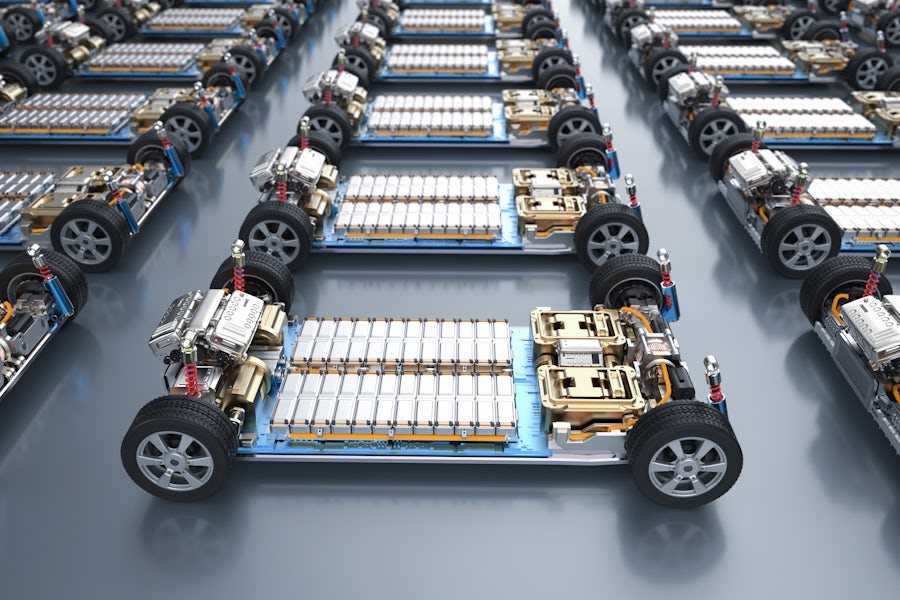 Silver battery cells on an electric vehicle chassis with four wheels and electric motors on the front and rear of the vehicle..