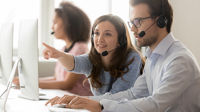 Employees with headsets working in a support service center.