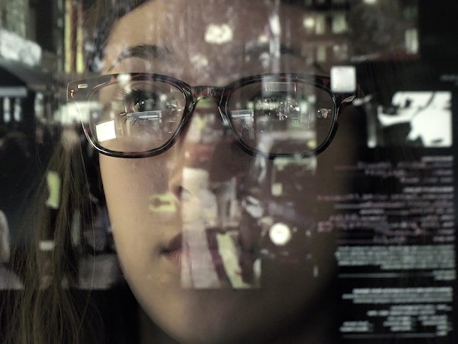 Woman looking through a window on which data is reflected