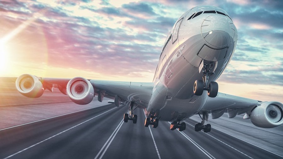 MBSE methodology is used in aerospace to make aircraft like this passenger jet shown taking off from a runway with illuminated clouds in the background