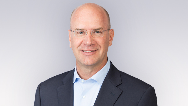 Professional headshot of Joe Bohman, posed and smiling against a neutral background.