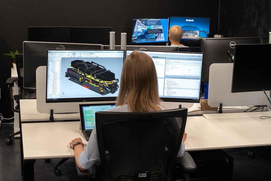 Eine Frau arbeitet an einem Computer an einem digitalen Rendering eines Maschinenteils auf Software für CAD in der Cloud.