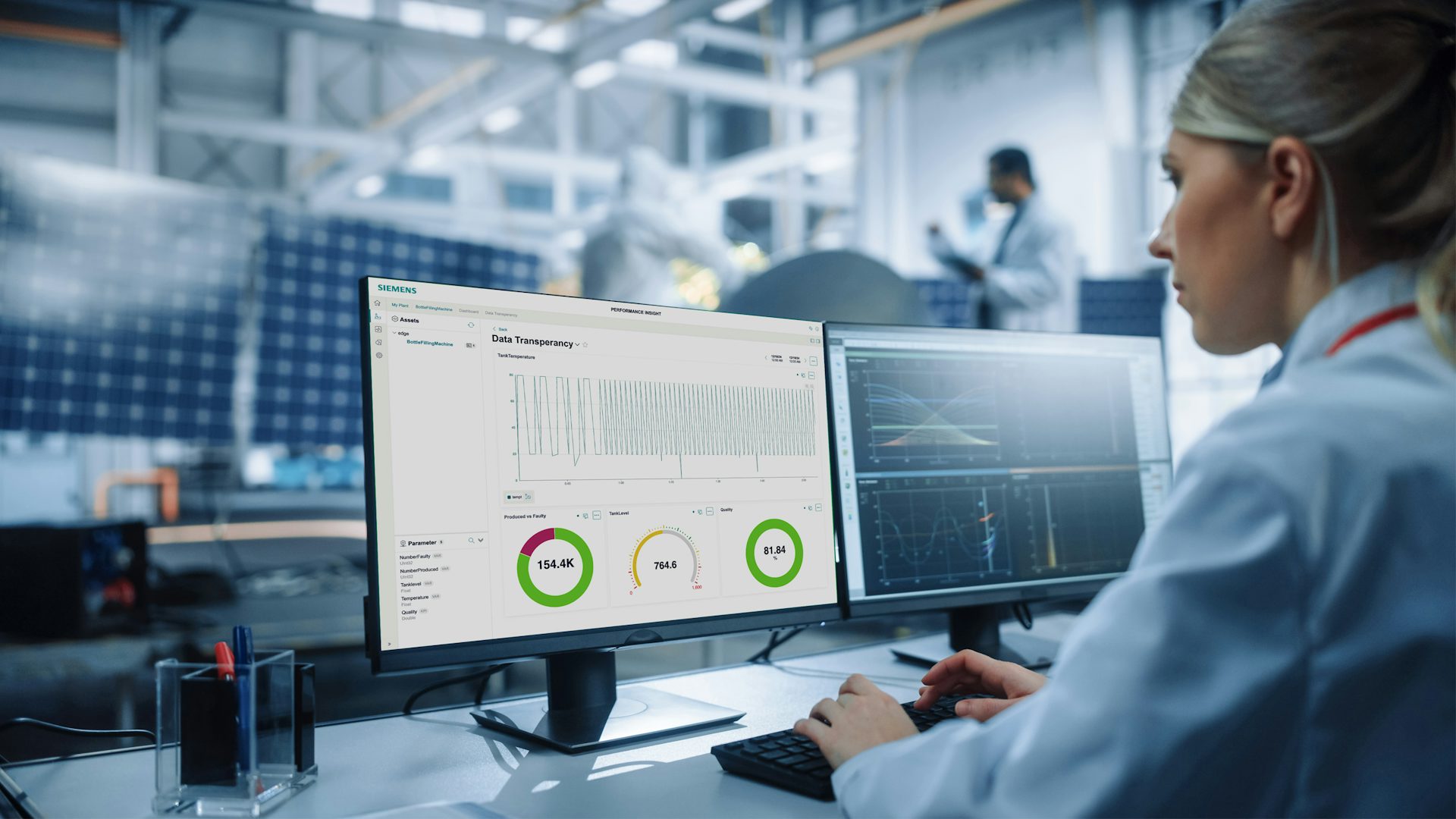 Female engineer sitting at desk using Siemens Industrial Edge software in a manufacturing facility.