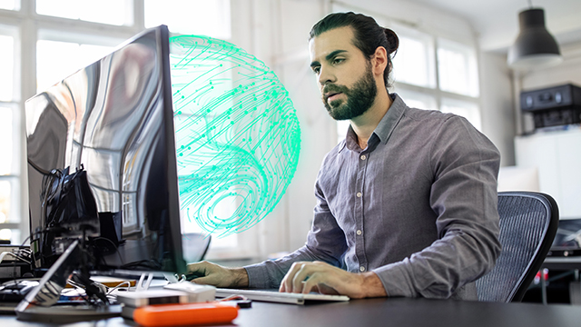 Guy at the desk in front a computer. 