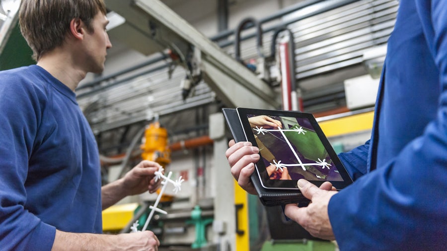 Two quality inspectors check the final product from an industrial machine.