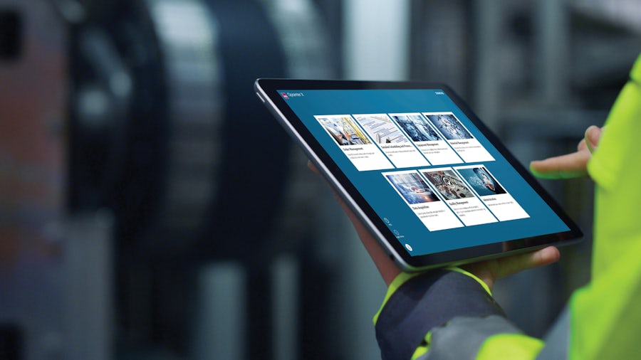 An engineer in a high-visibility jacket observing a modeled part on a tablet