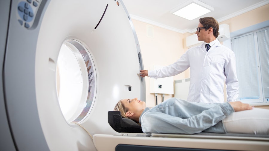 Medical professional pushing a button on a machine for patient getting a CT scan that has gone through medical device design control.