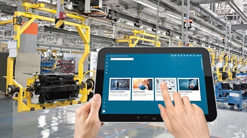 Zwei Hände, die ein Tablet in einer Produktionsstätte halten, in der eine Software zum Management der Produktionsabläufe verwendet wird.