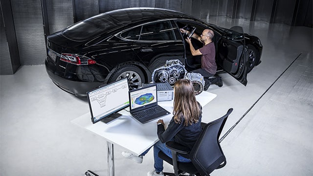 Two people using System NVH performance prediction software on a car.