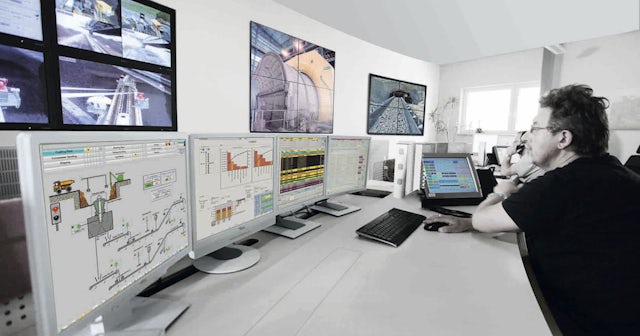 A mining company engineer using advanced software on a suite of connected computer monitors.