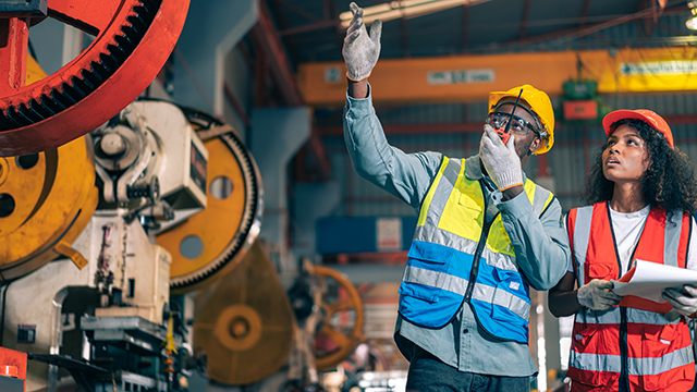 Two engineers observing machine conditions in a factory. The engineers are using Insight Hub solutions to monitor data visualization and performance. 