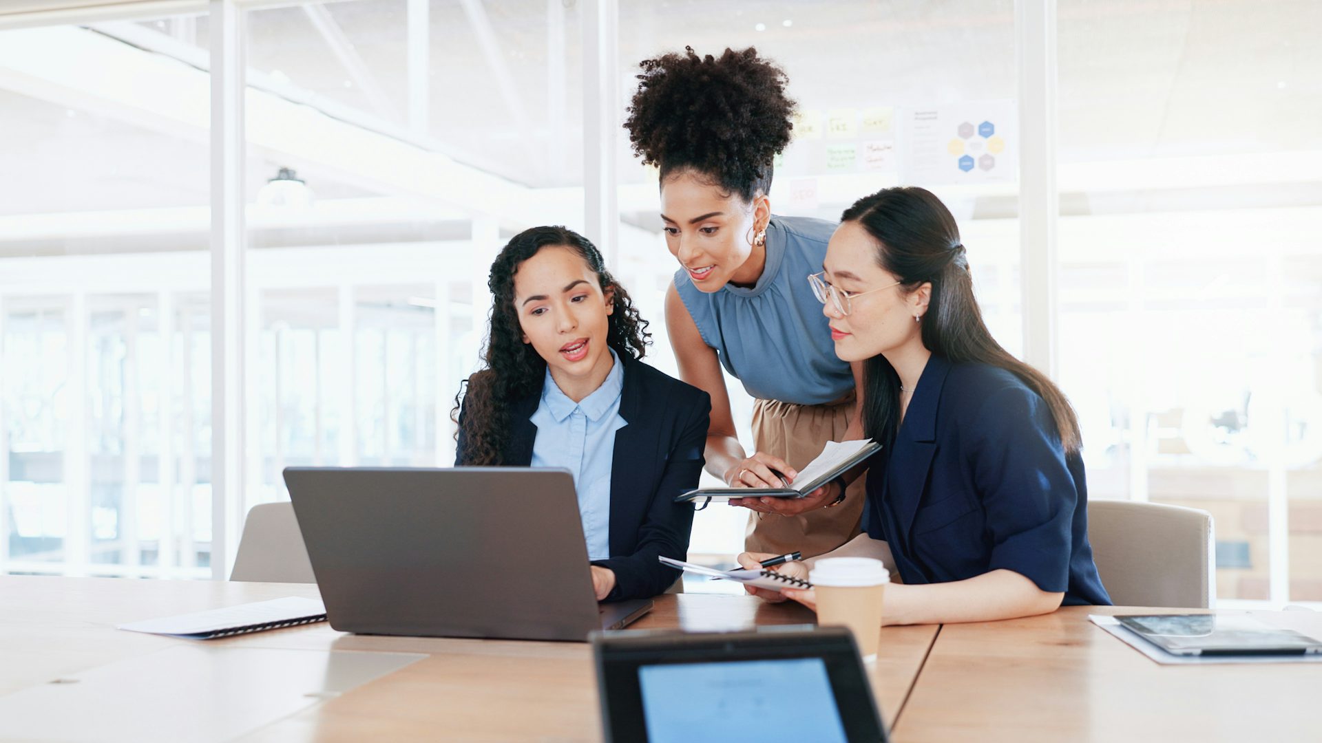 Tres mujeres colaborando en un ordenador en una oficina.