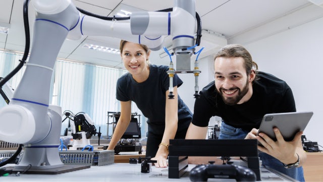 Mujer y hombre en un laboratorio mirando un brazo robótico