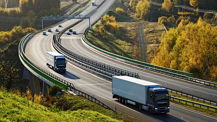 Zwei Logistik-LKWs fahren auf einer Autobahn auf dem Land.