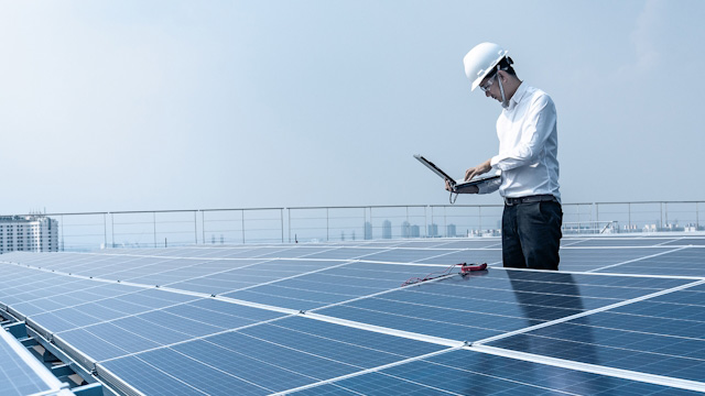 Man working on a computer working near solar panels.