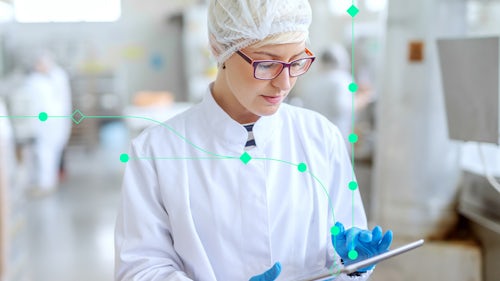 Female engineer in lab gear using a tablet for semiconductor plant operations and data analysis