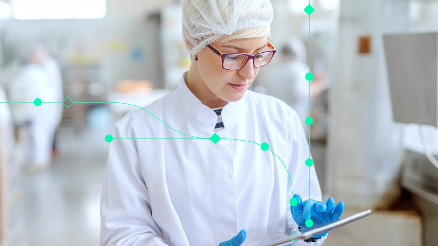 Female engineer in lab gear using a tablet for semiconductor plant operations and data analysis