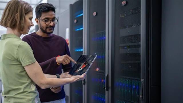 Two engineers discussing data on a table in a high-tech data center.