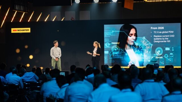 Tony Hemmelgarn presenting on stage at Realize LIVE in front of an AI icon on the screen.