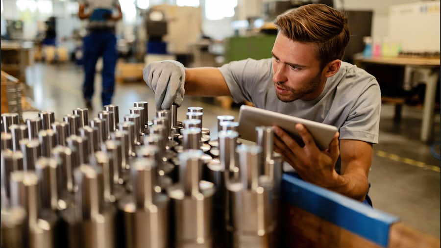  Person looking at machined parts that are placed on a table ready for inspection. 