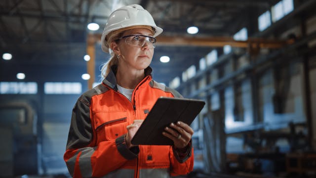 Frau in einer Fabrik mit einem Tablet.