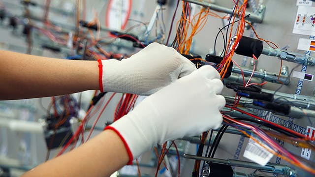 A person in white gloves assembling a harness formboard design.