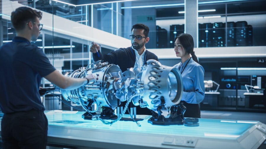 Team of engineers collaborating around a turbine prototype in a digital design environment.