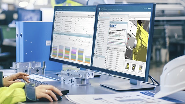 작업자가 제조 현장에서 컴퓨터 화면에 표시된 Teamcenter Easy Plan 소프트웨어를 통해 어셈블리 프로세스 세부 정보를 검토하고 있는 이미지.