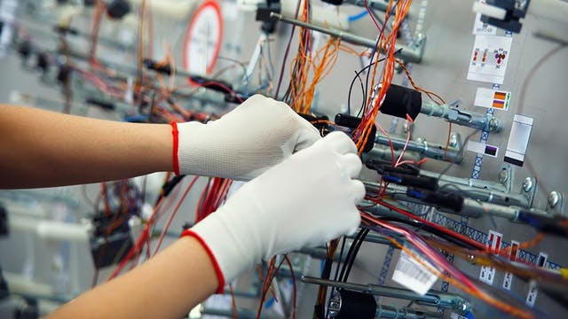 A person in white gloves assembling a harness formboard design.