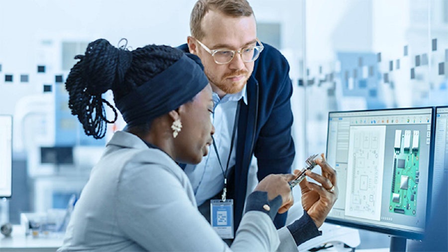 Two electronics company employees reviewing physical and virtual prototype.