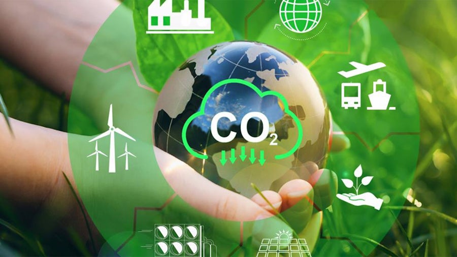 Hands holding Earth with green circle with sustainable industry icons and a lowering CO2 cloud