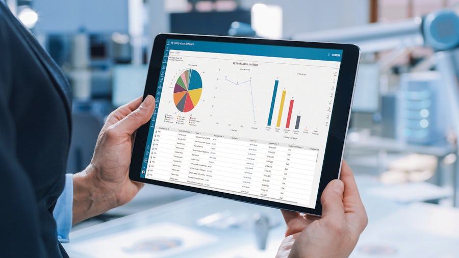 Un responsabile di produzione esamina un rapporto sulla qualità del sistema QMS su un tablet dall'area di produzione.