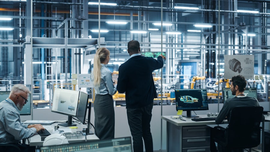 Two product managers in a factory overseeing an automotive assembly line.