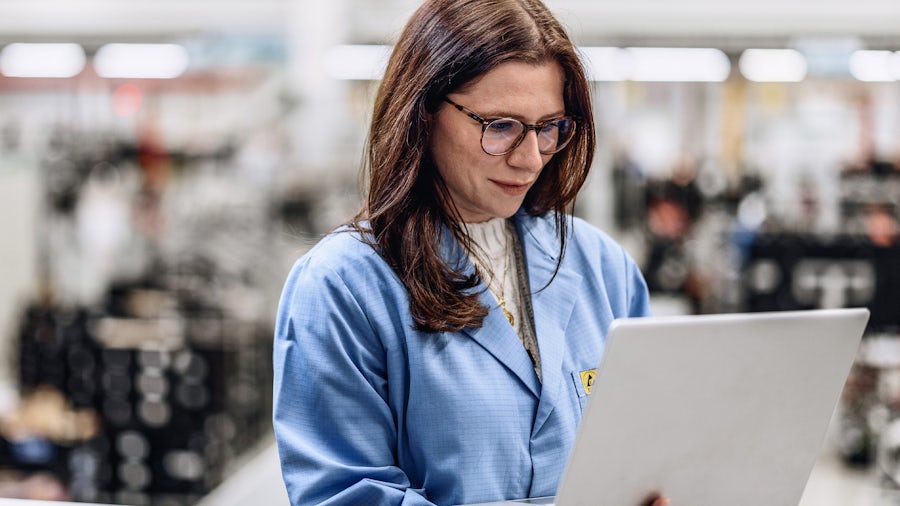 An engineer looks at machine performance on her laptop in a factory.