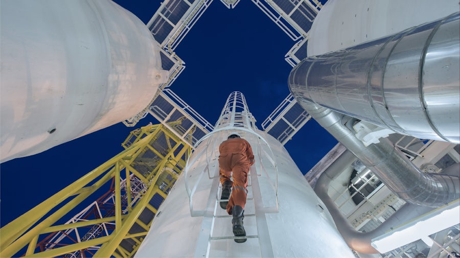 Person climbing up ladder inside power plant. 